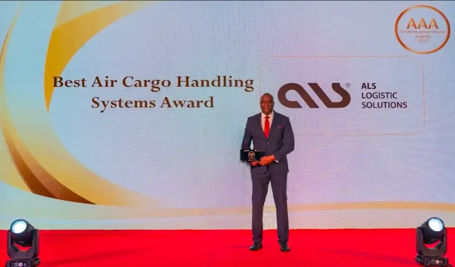 ALS representative holding the Best Air Cargo Handling Systems Award on a red stage at the Aviation Achievement Awards